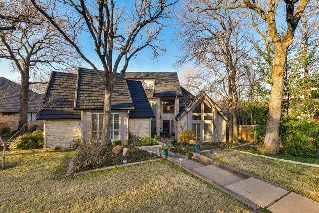 Stone house with black roof and yard.