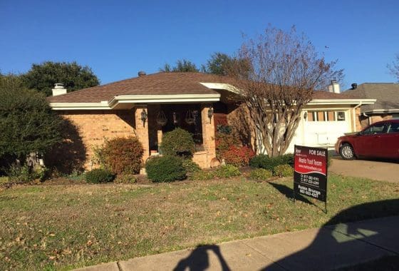 Brick house for sale with a red car.