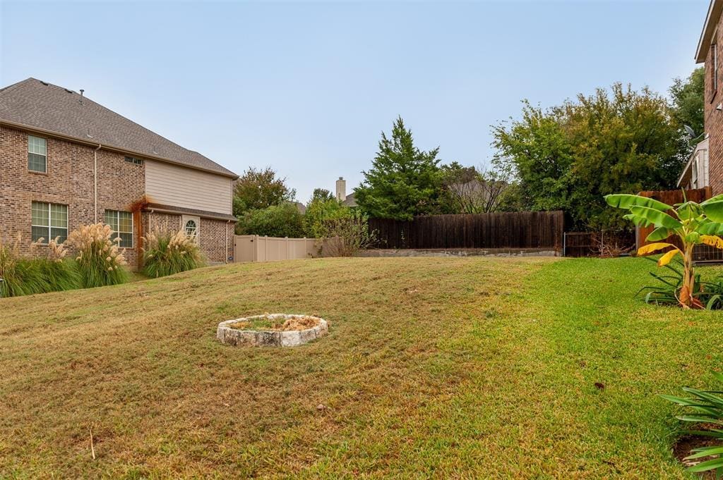 Backyard with grass, fence, and a house.