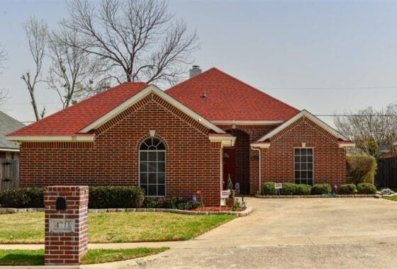 Brick house with red roof and driveway.