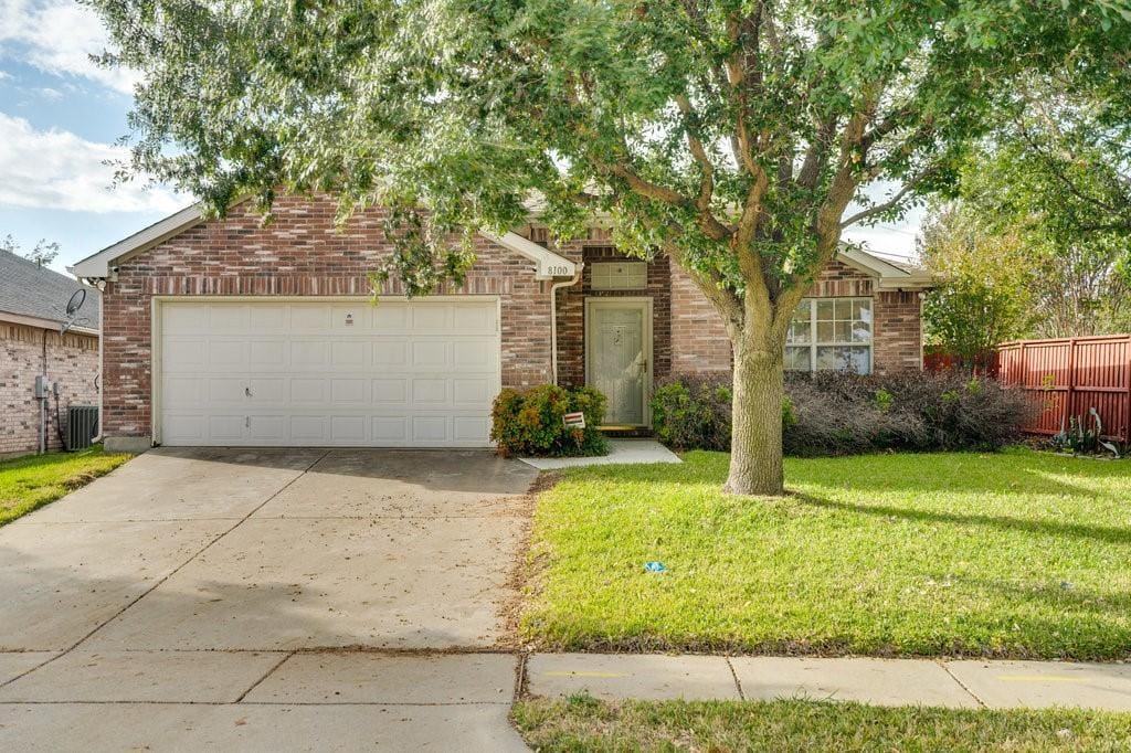 Brick house with white garage door and front yard.