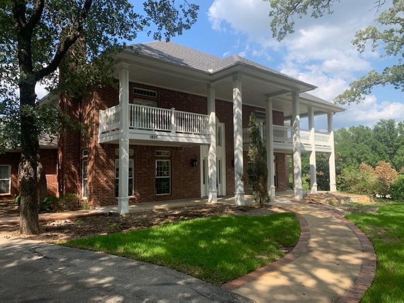 Brick house with white columns and porch.