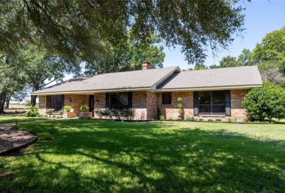 Brick ranch house with green lawn.