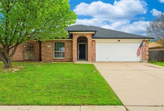 Brick house with green lawn and driveway.