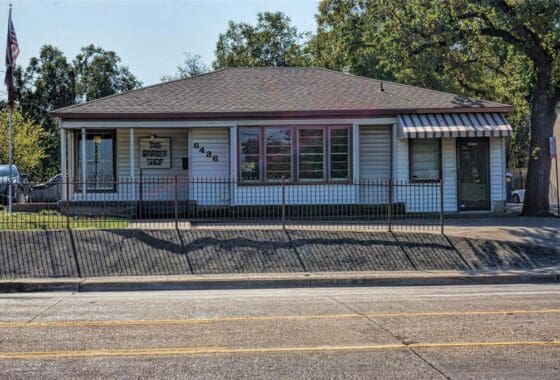 White building with black fence and striped awning.