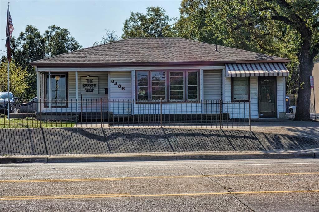 White building with black fence and striped awning.