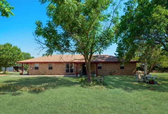 Brick house with trees and green grass.