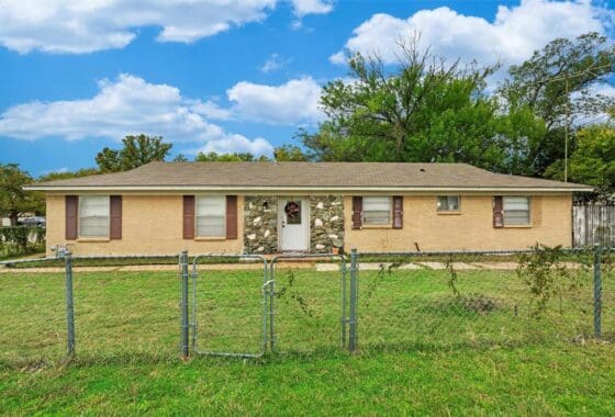 Brick house with stone accents and a fence.